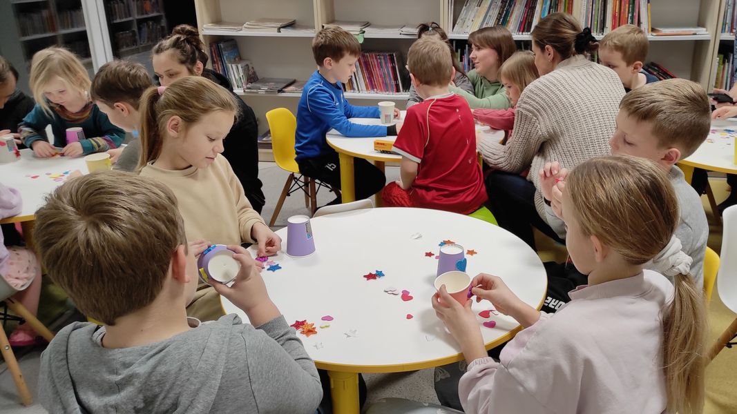 Dzieci tworzą pracę plastyczną: dzwonki z kubków papierowych.