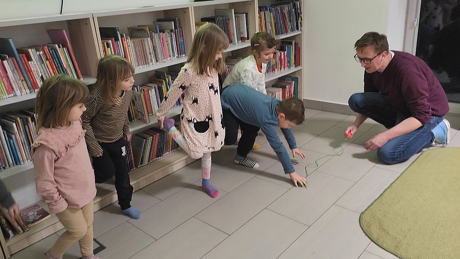 Dzieci biorą udział w zabawie ruchowej, łapią żabę - zabawkę.